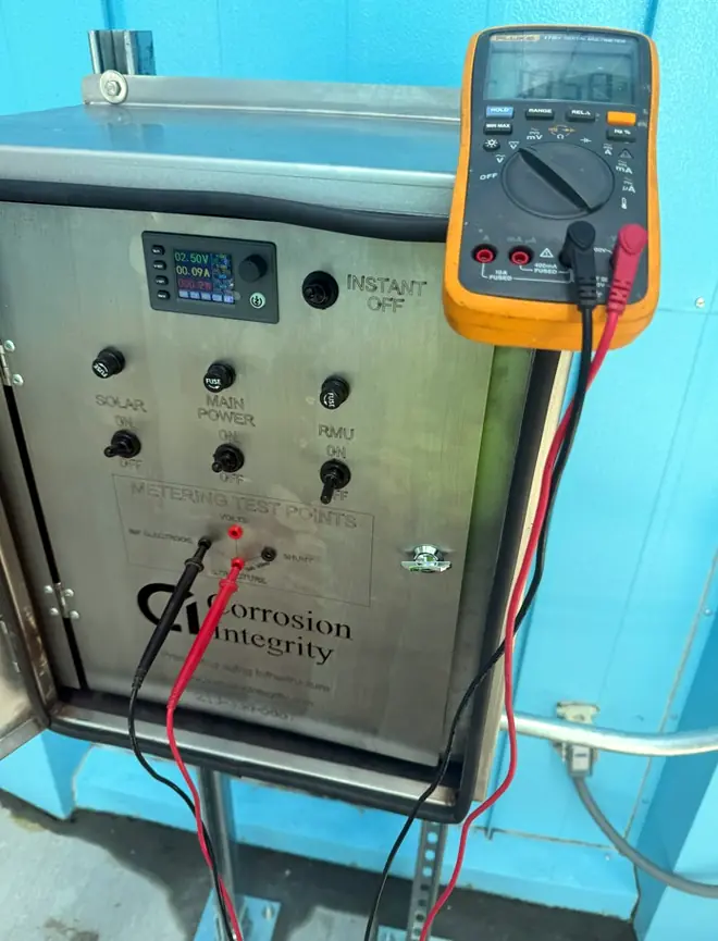 Technician taking a reading at the controller test points with a digital multimeter during commissioning
